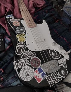 an electric guitar with many stickers on it's body and neck, sitting on a blanket