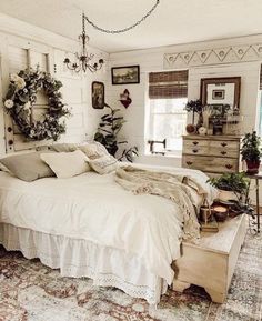 a bed with white sheets and pillows in a bedroom next to a dresser, potted plants on the wall