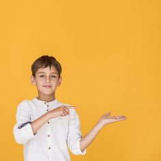 a young boy is holding out his hand while standing against a yellow background with an orange backdrop