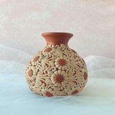 a brown vase sitting on top of a blue tablecloth covered floor next to a white wall