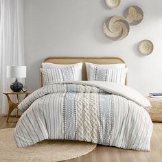 a bed with white and blue striped comforter in a bedroom next to a window