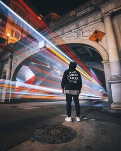 a person standing in the middle of an empty street with blurry lights behind them