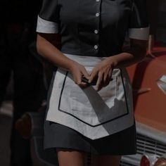 a woman standing in front of an old car with her hands on her hip pocket