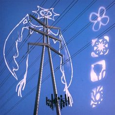 an electric pole with some drawings on it and power lines in the foreground, against a blue sky