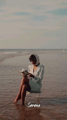 a woman sitting on a beach reading a book