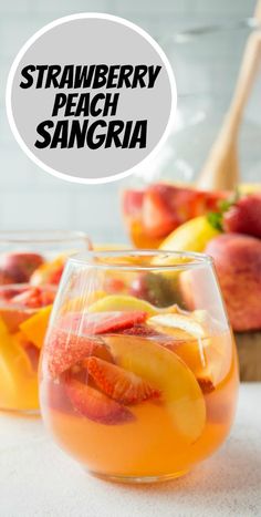 two glasses filled with peach sangria on top of a white table next to sliced fruit