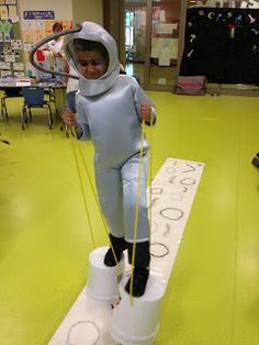 a young boy in a space suit standing on top of a bucket and holding a rope