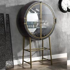 a round mirror sitting on top of a metal stand next to a wall mounted clock