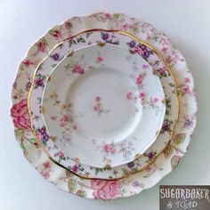 three floral plates stacked on top of each other with gold rims and pink flowers