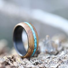 a wooden ring with turquoise inlays on top of some wood and rock chips