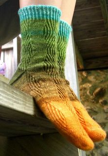 a person wearing green and orange socks on top of a wooden fence