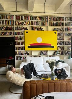 a person laying on a couch in front of a bookshelf filled with books