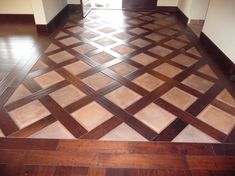 an empty room with wooden floors and tiled flooring on the walls, in front of a doorway