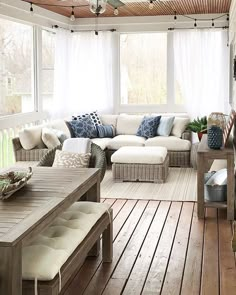 an outdoor living room with white couches and blue pillows on the back porch area