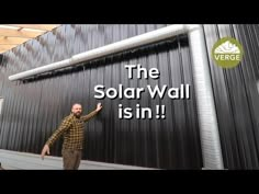 a man standing in front of a building with the words the solar wall is in