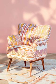 a colorful chair sitting on top of a tile floor next to a pink painted wall