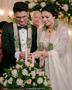 a man and woman standing next to each other in front of a cake with candles