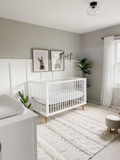 a baby's room with a white crib and pictures on the wall