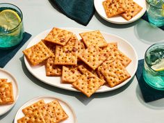 some crackers are sitting on plates with lemon wedges and water in the background