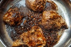 three pieces of meat are in a pan with black beans on the bottom and sides