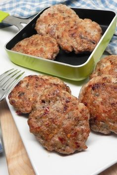 three hamburger patties on a plate with a fork and knife next to the pan