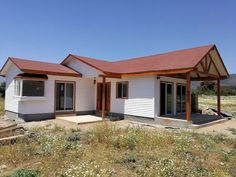 a small white house sitting on top of a dry grass field