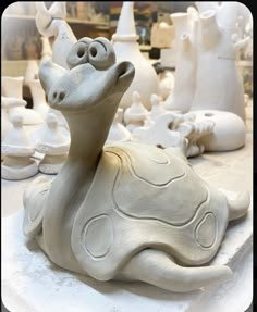 a ceramic animal sitting on top of a white table next to other clay animals and vases