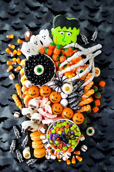 a table topped with lots of candy and candies covered in halloween decorations on top of a black surface