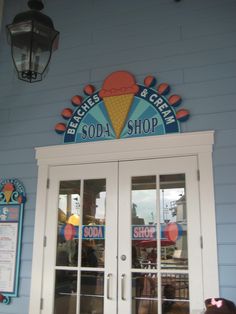 an ice cream shop sign on the side of a blue building with white doors and windows