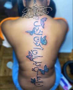 the back of a man's tattoo with butterflies on his upper and lower back