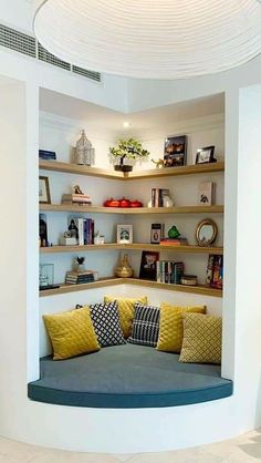 a circular couch in the corner of a room with bookshelves on either side