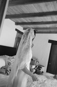 a woman in a wedding dress standing on a bed with a veil over her head