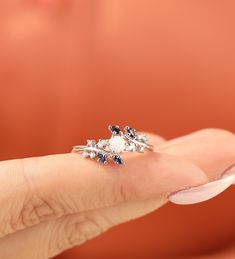 a woman's hand holding an engagement ring with blue and white stones on it