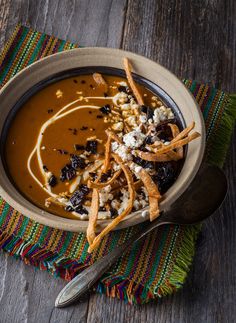 a bowl of soup on a wooden table with spoons and napkin next to it