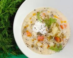 a bowl of soup with carrots, celery and sour cream