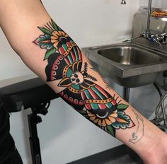 a person with a tattoo on their arm holding a sink and faucet in the background