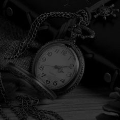 an old pocket watch sitting on top of a table next to some chains and flowers