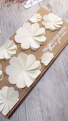 a card with paper flowers on it sitting on top of a piece of brown paper