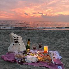 a bottle of wine and some food on the sand at the beach near the ocean