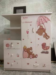 a baby changing table with an umbrella and teddy bear decals on the top shelf