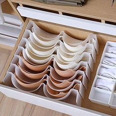 an open drawer filled with lots of white dishes on top of a wooden countertop