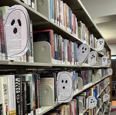 several books are on shelves in a library with ghost faces drawn on the book covers