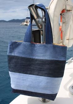 a blue and black striped tote bag hanging off the side of a boat