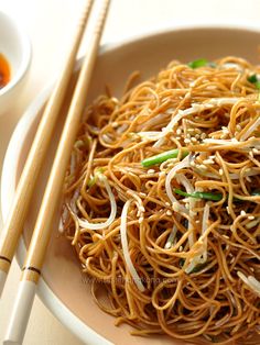 a plate full of noodles with chopsticks next to it