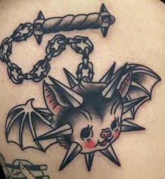 a bat tattoo on the back of a woman's shoulder, with chains hanging from it