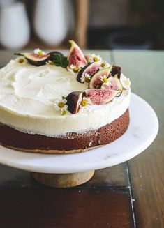 a cake with white frosting and figs on top sits on a plate, ready to be eaten