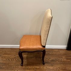 a brown leather chair sitting on top of a hard wood floor next to a wall