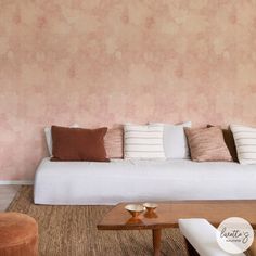 a living room filled with furniture and a white couch in front of a pink wall