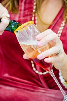 a woman in a red dress is holding a wine glass with a green and yellow garnish on it