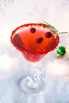 a close up of a drink in a wine glass with olives on the rim